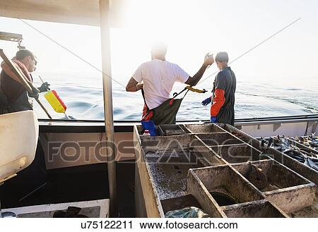 Stock Image - Fishermen working on boat. Fotosearch