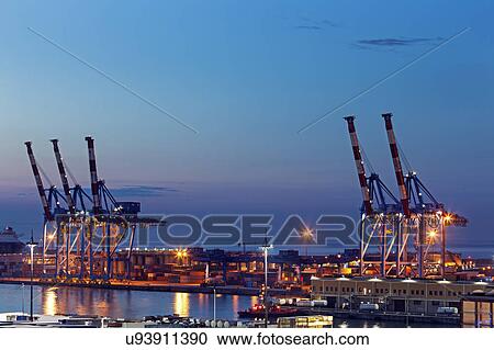 Stock Image - Genoa harbor cranes at sunrise. Fotosearch