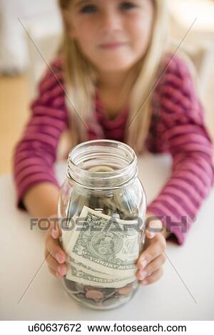 Girl (6-7) holding jar with savings View Large Photo Image Stock Image - Girl (6-7) holding jar with savings. Fotosearch