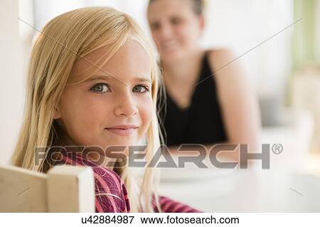 Stock Photo - Girl (6-7) looking at camera and woman in background. Fotosearch