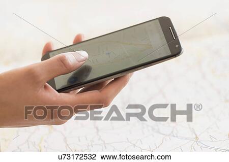 Hand holding smart phone, map in background View Large Photo Image Stock Image - Hand holding smart phone, map in background. Fotosearch
