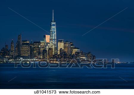 Stock Image - Illuminated cityscape reflecting in river. Fotosearch