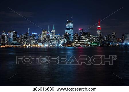 Stock Image - Illuminated cityscape reflecting in river. Fotosearch