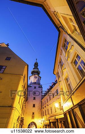Stock Image - Illuminated townhouses and tower at dusk. Fotosearch