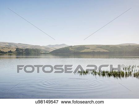Stock Photo - Lake by hills and clear sky. Fotosearch