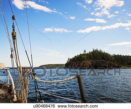 Stock Photograph - Lighthouse on cliff seen from sailboat. Fotosearch