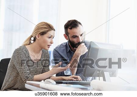 Man and woman looking at computer in office View Large Photo Image Stock Photo - Man and woman looking at computer in office. Fotosearch