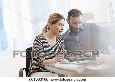 Man and woman looking at computer in office View Large Photo Image Stock Photograph - Man and woman looking at computer in office. Fotosearch