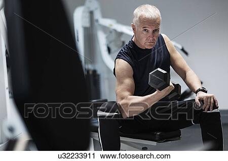 Man exercising with dumbbells on weight bench View Large Photo Image Stock Image - Man exercising with dumbbells on weight bench. Fotosearch
