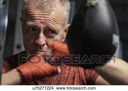 Picture - Man in health club hitting speed bag. Fotosearch