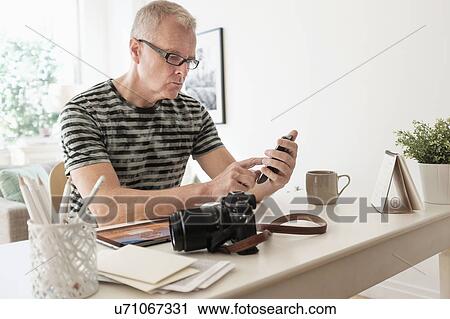 Man in home office using smartphone View Large Photo Image Stock Image - Man in home office using smartphone. Fotosearch
