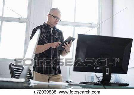 Stock Photo - Man in office using digital tablet. Fotosearch