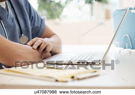 Man in scrubs using laptop View Large Photo Image Stock Photo - Man in scrubs using laptop. Fotosearch