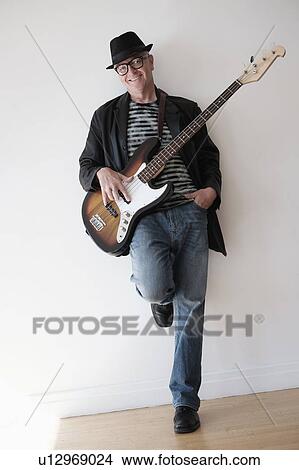 Picture - Man playing bass guitar in empty room. Fotosearch