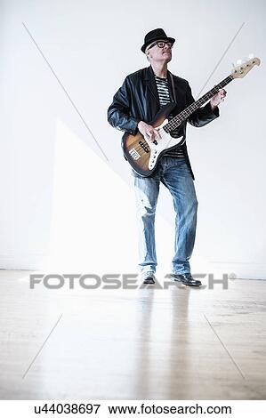 Stock Photo - Man playing bass guitar in empty room. Fotosearch