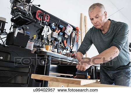 Man working with wood in home workshop View Large Photo Image Stock Photo - Man working with wood in home workshop. Fotosearch