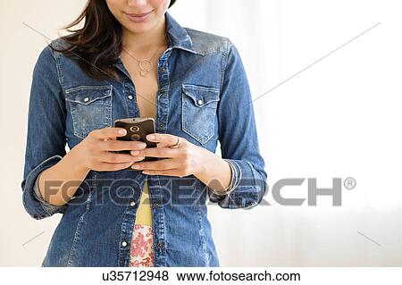Stock Photo - Mid-section of young woman texting. Fotosearch