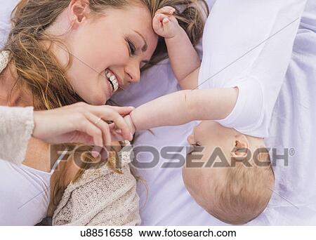 Stock Photo - Mother and baby (6-11 months) lying down and playing. Fotosearch
