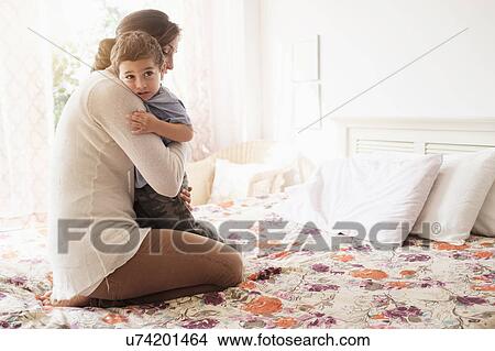 Picture - Mother embracing son (2-3) on bed. Fotosearch
