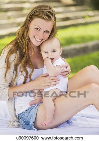Mother holding baby (6-11 months) on lap View Large Photo Image Stock Image - Mother holding baby (6-11 months) on lap. Fotosearch