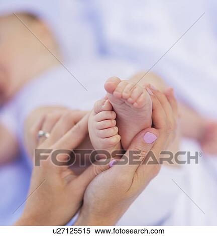 Stock Photography - Mother holding baby boy 's (6-11 months) feet. Fotosearch