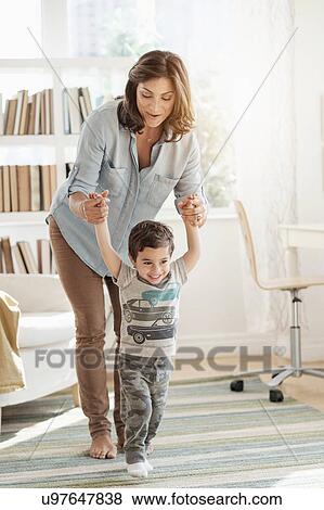 Stock Photo - Mother holding son (2-3) making first steps. Fotosearch