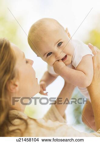 Picture - Mother holding up baby boy (6-11 months). Fotosearch