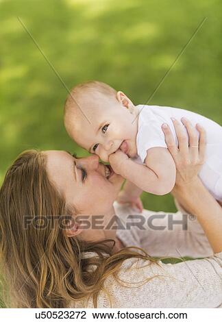 Stock Image - Mother holding up baby boy (6-11 months). Fotosearch