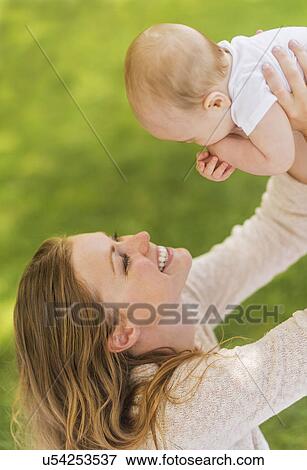 Stock Photo - Mother holding up baby boy (6-11 months). Fotosearch