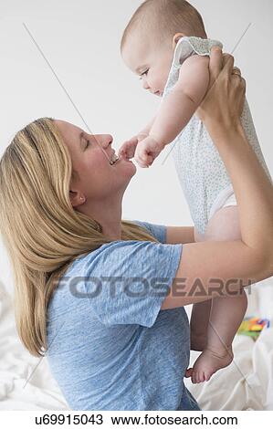 Stock Image - Mother lifting baby daughter (12-17 months). Fotosearch