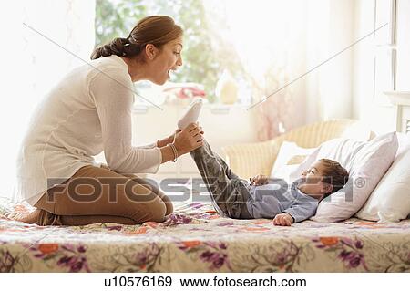 Stock Photo - Mother playing with son (2-3) on bed. Fotosearch