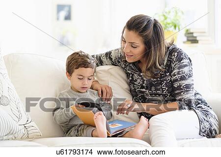 Picture - Mother reading with son (2-3) on sofa. Fotosearch