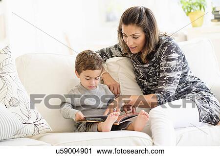 Stock Image - Mother reading with son (2-3) on sofa. Fotosearch