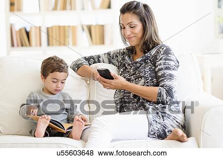 Mother texting while son (2-3) reading on sofa View Large Photo Image Stock Photo - Mother texting while son (2-3) reading on sofa. Fotosearch