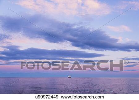 Stock Photo - Pastel-colored sunset seascape with sailboat. Fotosearch