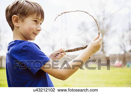 Stock Image - Portrait of boy (6-7) with toy bow. Fotosearch