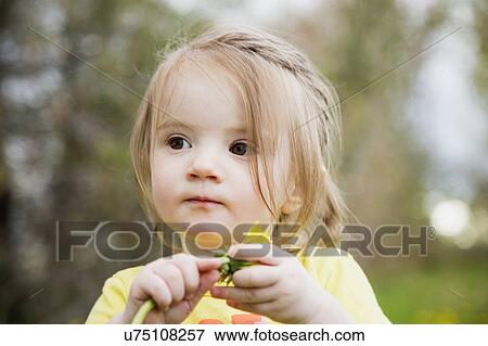 Stock Photo - Portrait of girl (2-3) holding flower. Fotosearch