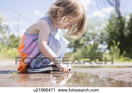 Stock Image - Portrait of girl (2-3) playing in puddle. Fotosearch