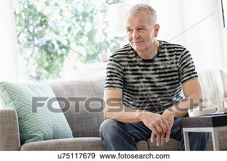 Portrait of man sitting on sofa at home View Large Photo Image Stock Photo - Portrait of man sitting on sofa at home. Fotosearch