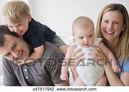 Stock Image - Portrait of parents with son (2-3) and baby daughter (12-17 months). Fotosearch