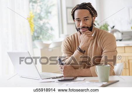 Portrait of young man with laptop at table View Large Photo Image Picture - Portrait of young man with laptop at table. Fotosearch