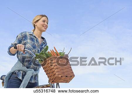 Stock Photo - Portrait of young woman with bicycle. Fotosearch