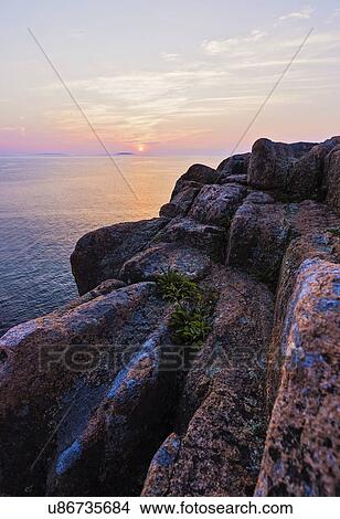 Picture - Rocky cliff by sea at sunrise. Fotosearch