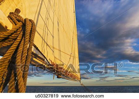 Stock Photo - Sail and ropes against sunset sky. Fotosearch
