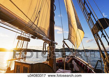 Stock Photo - Sailboat against sunset sky. Fotosearch