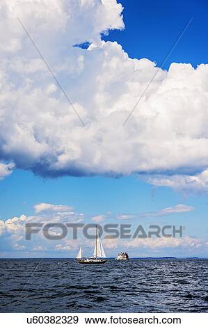 Stock Photo - Sailboat on sea and Rockland Harbor Breakwater Lighthouse in distance. Fotosearch