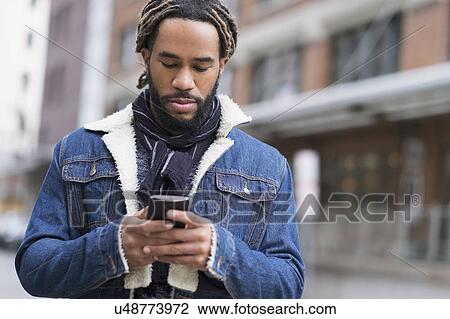 Serious man with dreadlocks using smart phone in street View Large Photo Image Stock Image - Serious man with dreadlocks using smart phone in street. Fotosearch