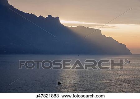 Stock Image - Silhouette of coastline at sunrise. Fotosearch