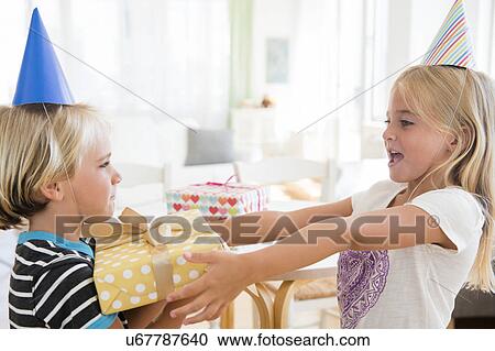 Sister (6-7) giving birthday present to brother (4-5) View Large Photo Image Stock Image - Sister (6-7) giving birthday present to brother (4-5). Fotosearch