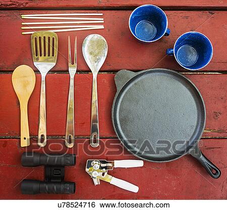 Stock Photograph - Skillet, cups and cooking utensils on picnic table. Fotosearch